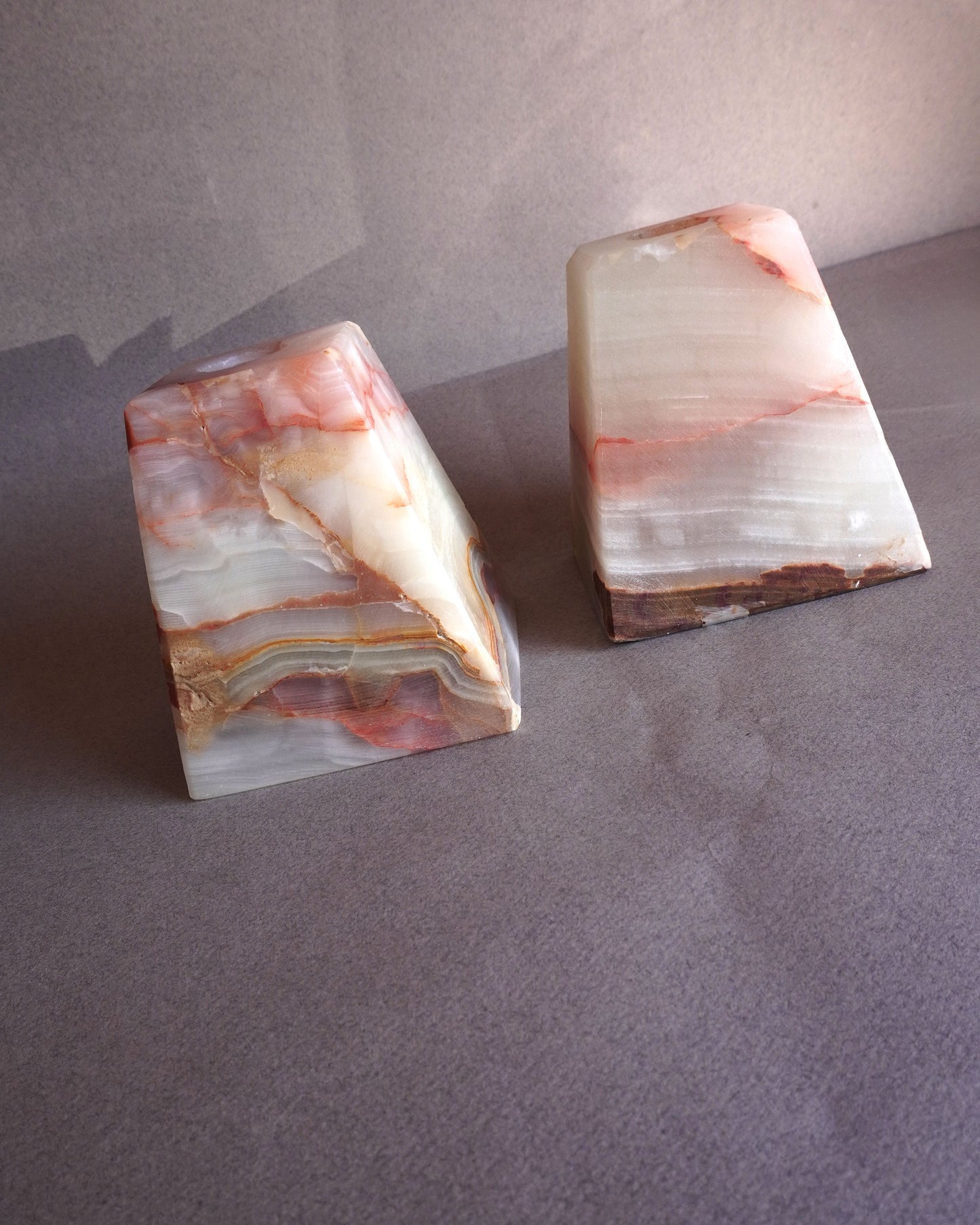 Two onyx stone bookends or candle holders on a gray surface with a neutral background