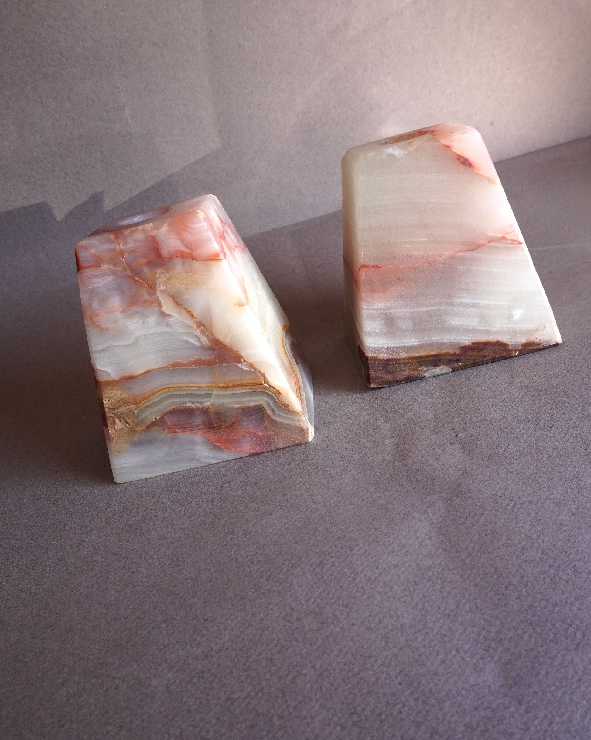 Two onyx stone bookends or candle holders on a gray surface with a neutral background