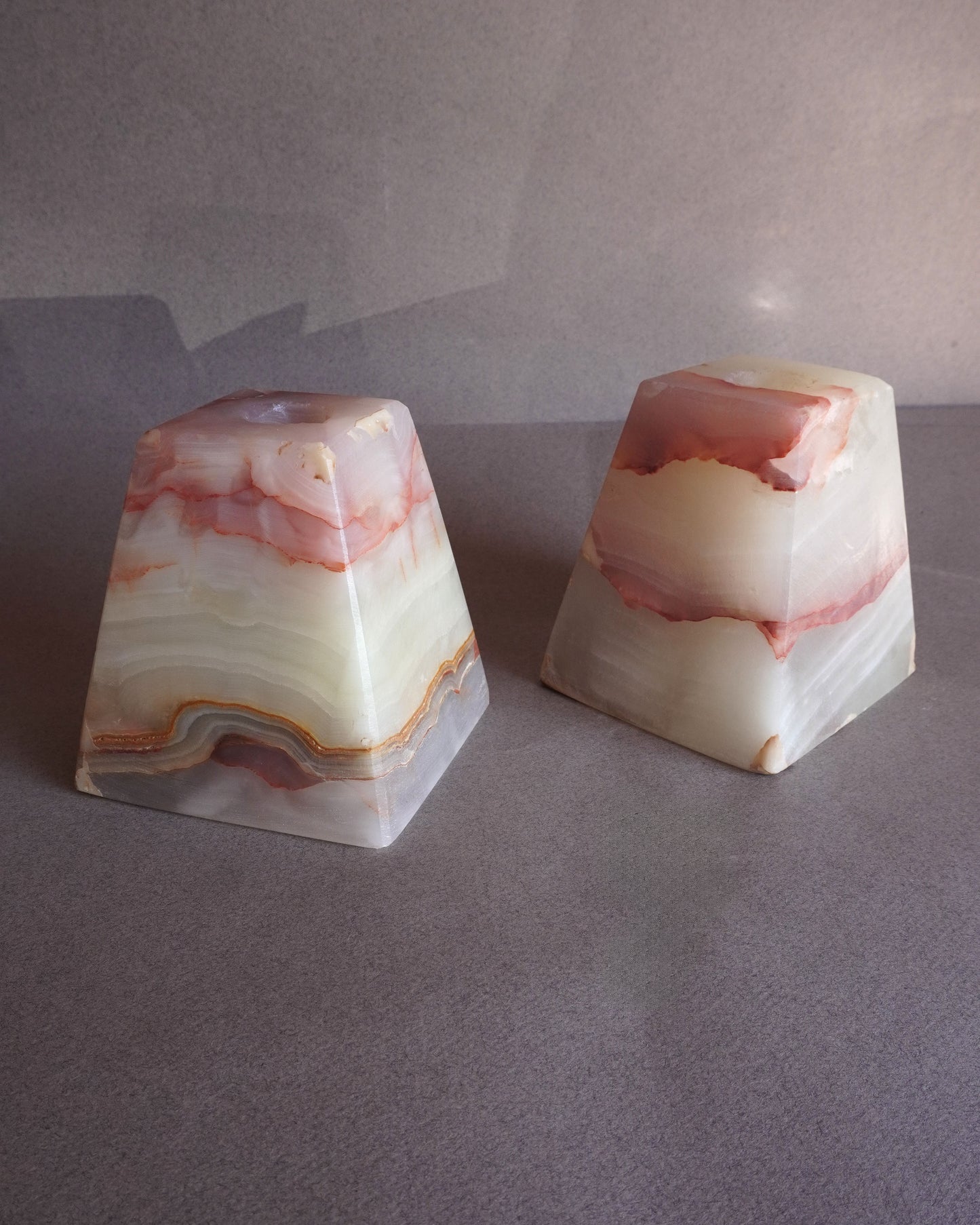 Two onyx candle holders with a marbled pattern on a gray surface.