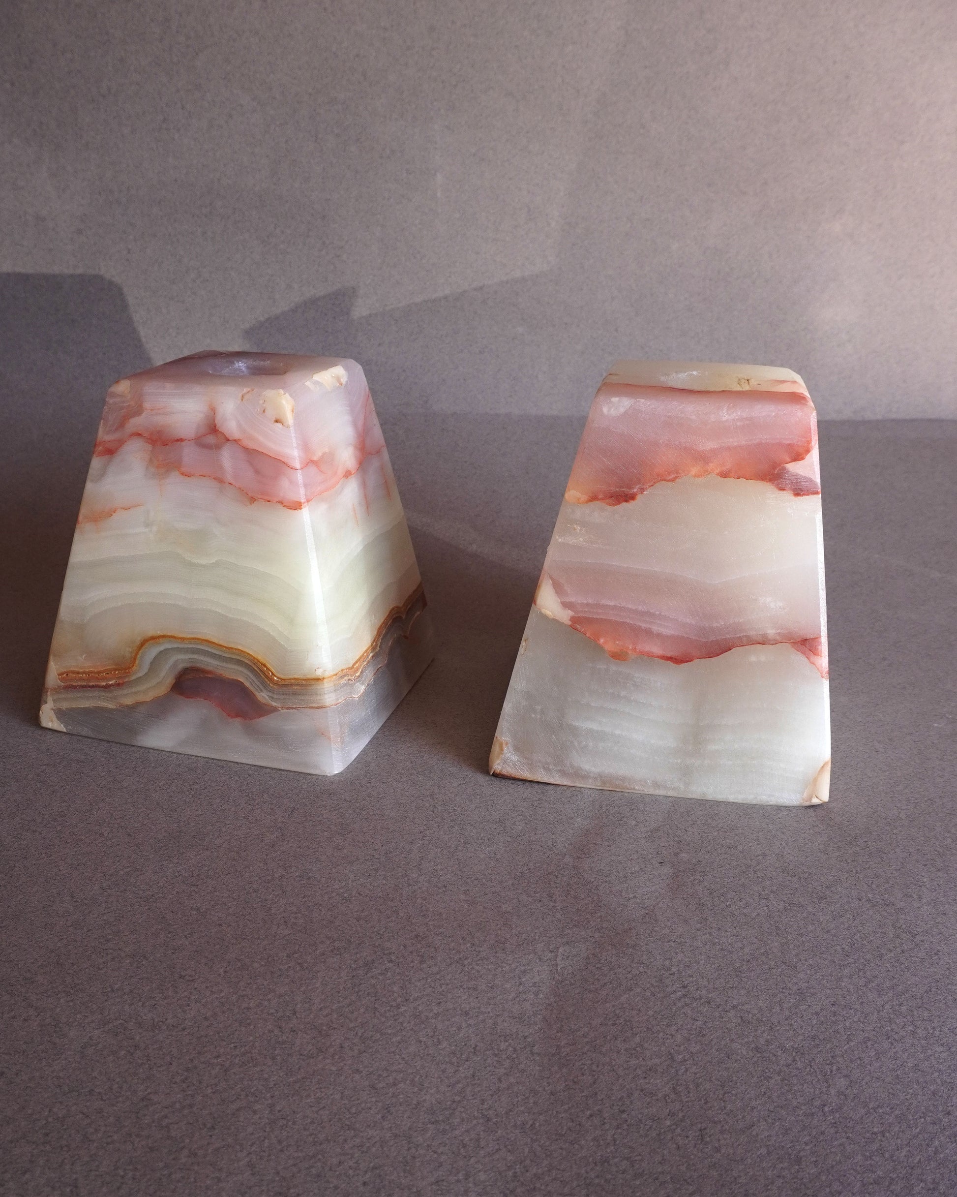 Two onyx stone bookends on a gray surface