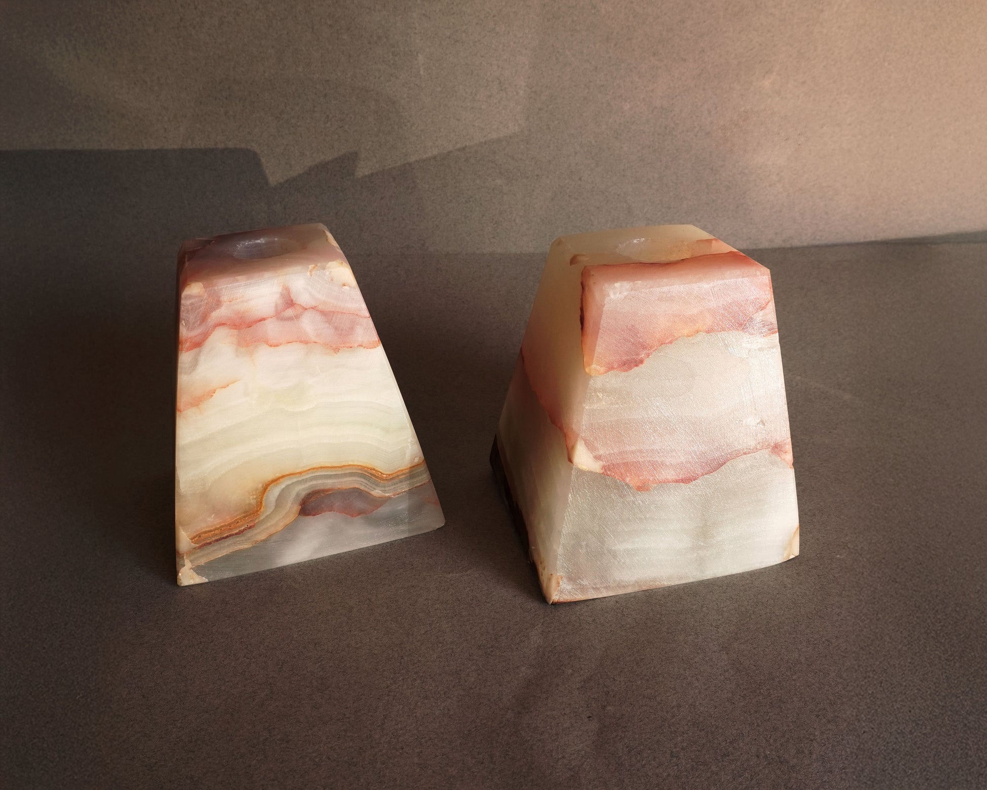 Two onyx bookends or candle holders with a marbled pattern on a dark surface.