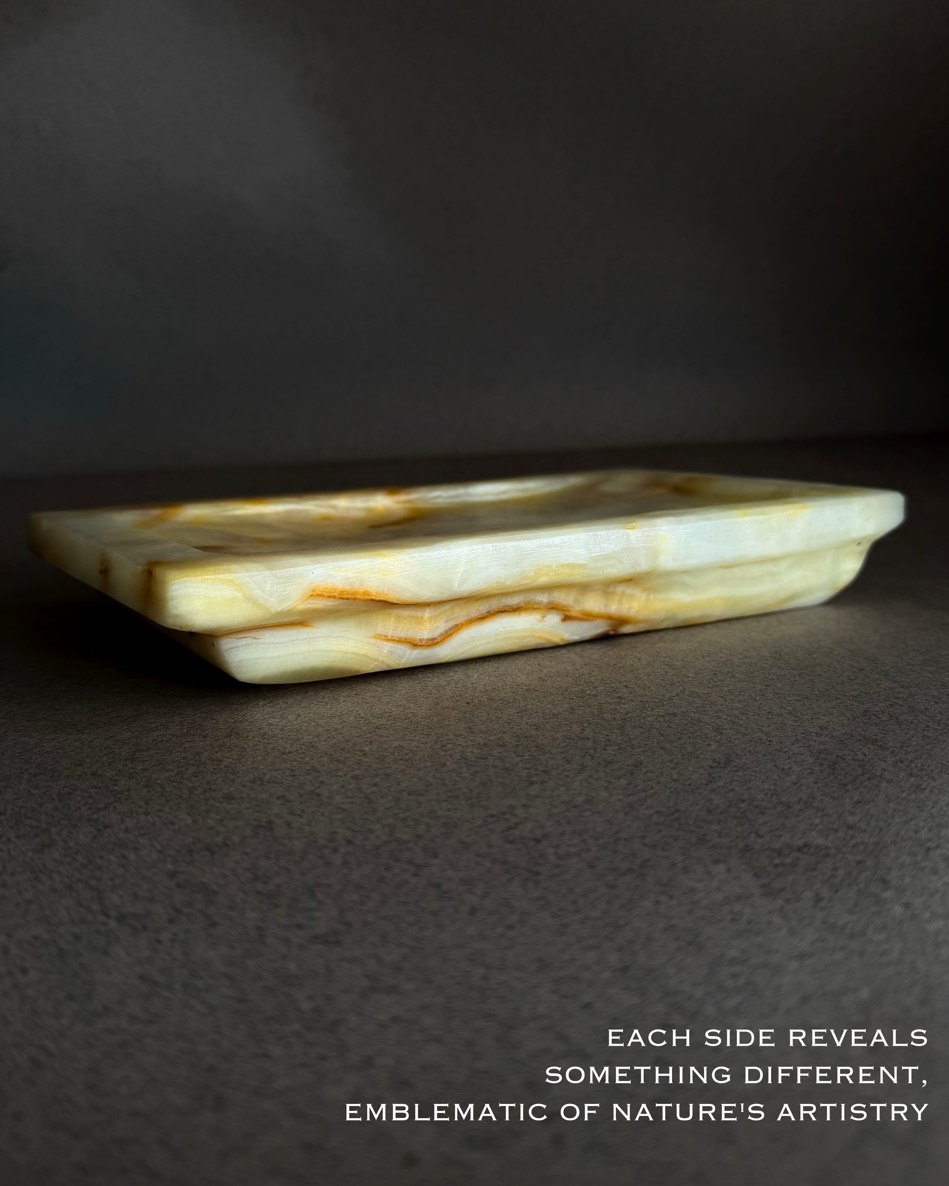 Side profile of rectangular onyx tray showing layered honey and amber veining and raw stone texture
