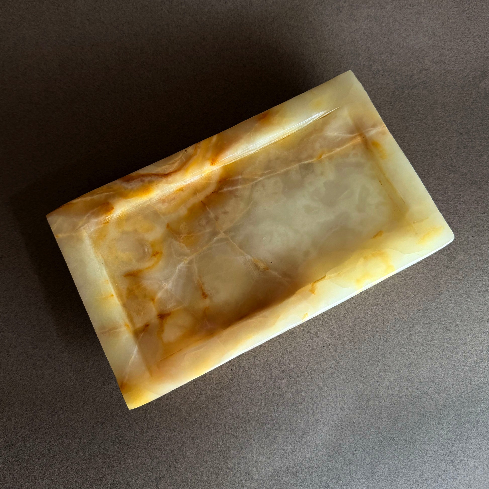 Rectangular stone vanity tray with marbled pattern on a dark surface