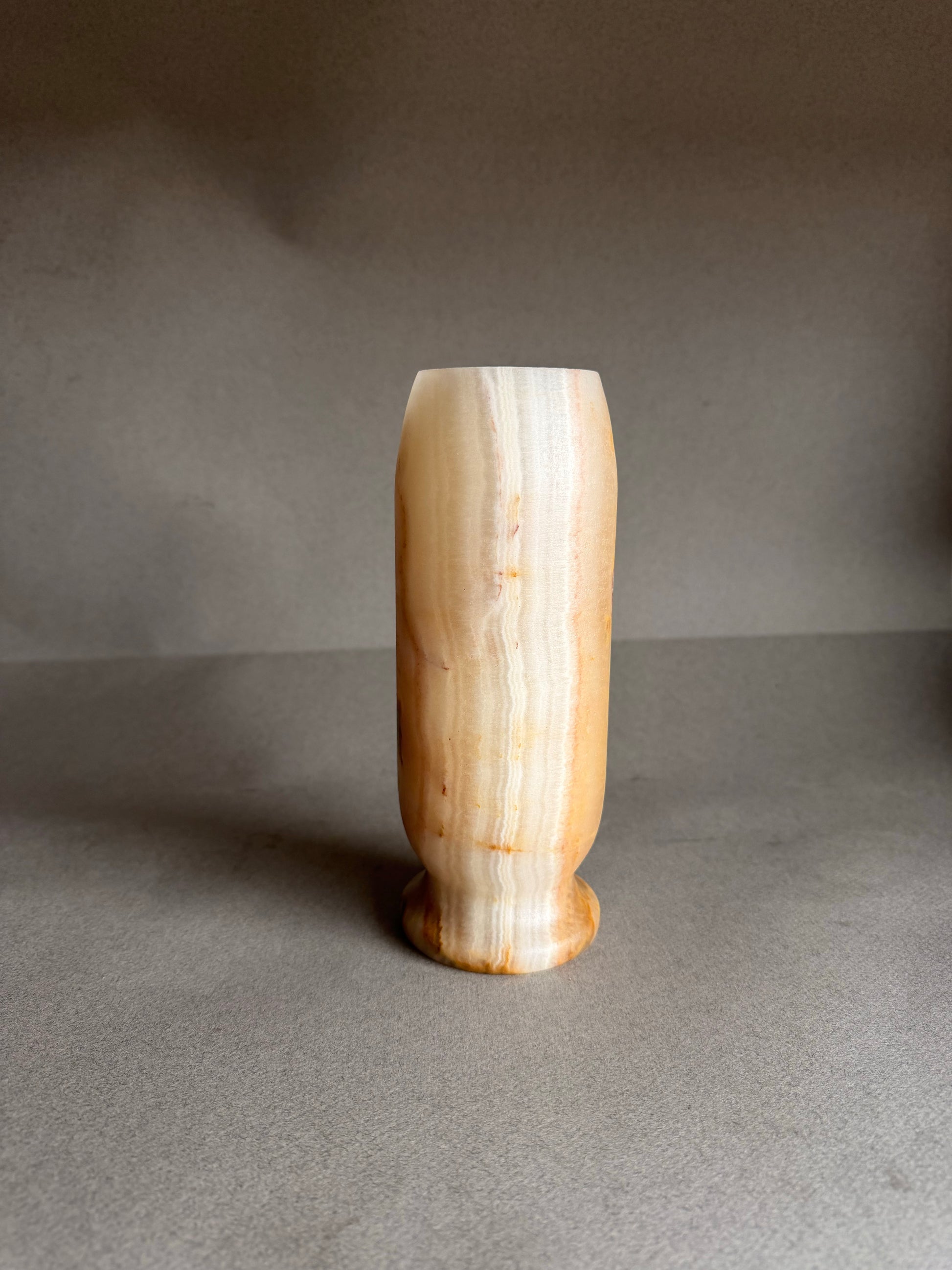 peach white orange honey  ceramic vase on a gray surface with a dark background