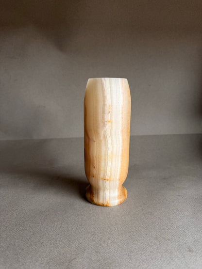 peach white orange honey  ceramic vase on a gray surface with a dark background