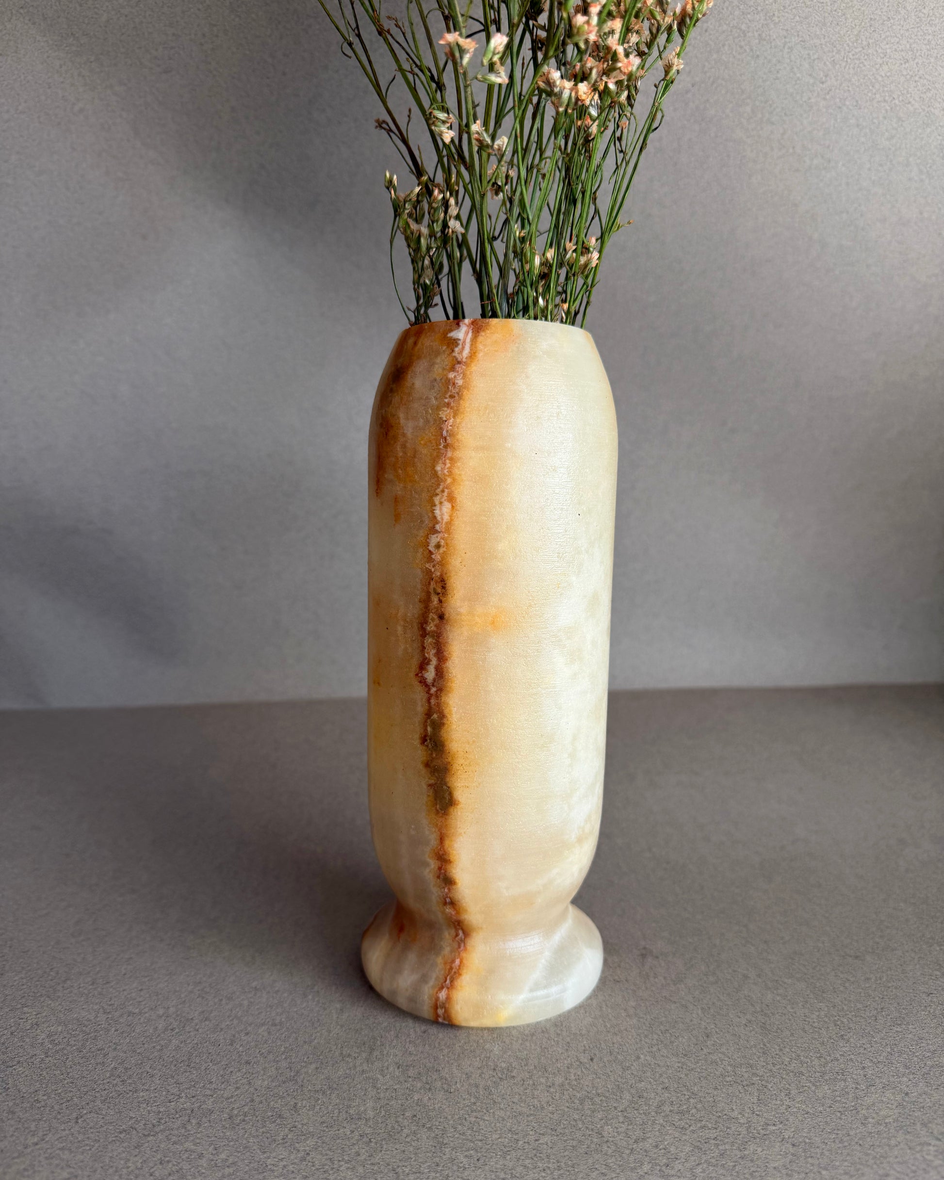 Decorative peach honey onyx marble stone vase with a natural stone pattern on a gray background