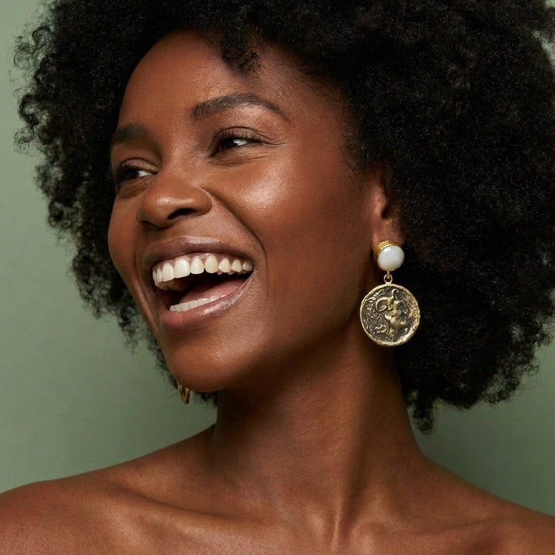 Model laughing while wearing freshwater pearl and antique gold coin drop earrings