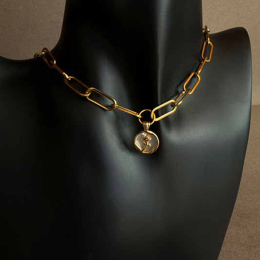 Modern gold chain necklace with mother of pearl pendant, soft iridescent pearl rose detail on neutral background
