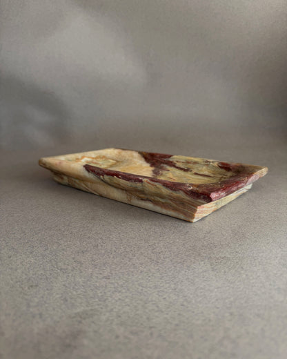 Stone catchall tray carved from solid onyx with painterly purple, chestnut, and moss green mineral patterns

