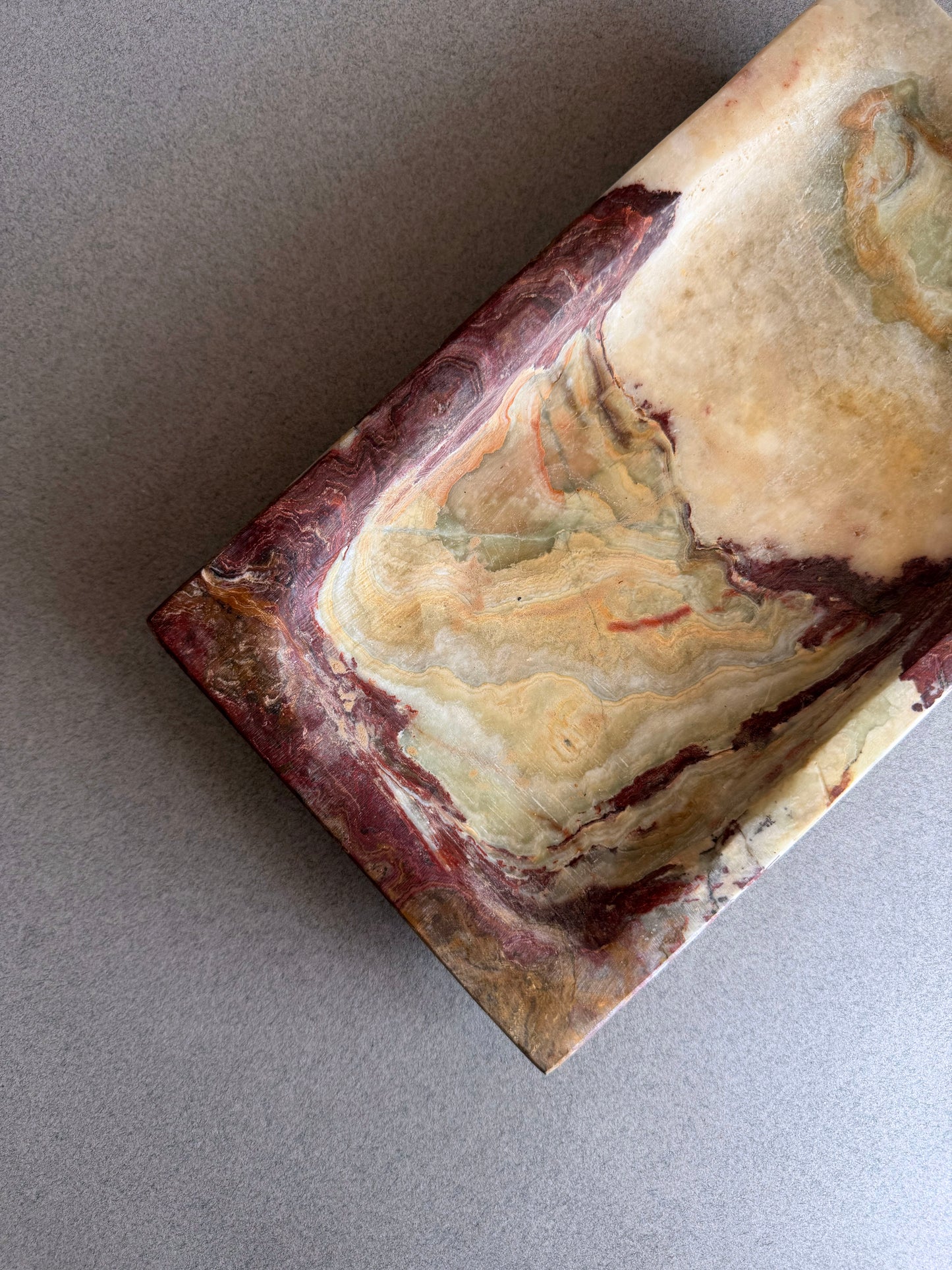 Organic modern onyx tray with raw stone texture and warm earth-toned veining on neutral background
