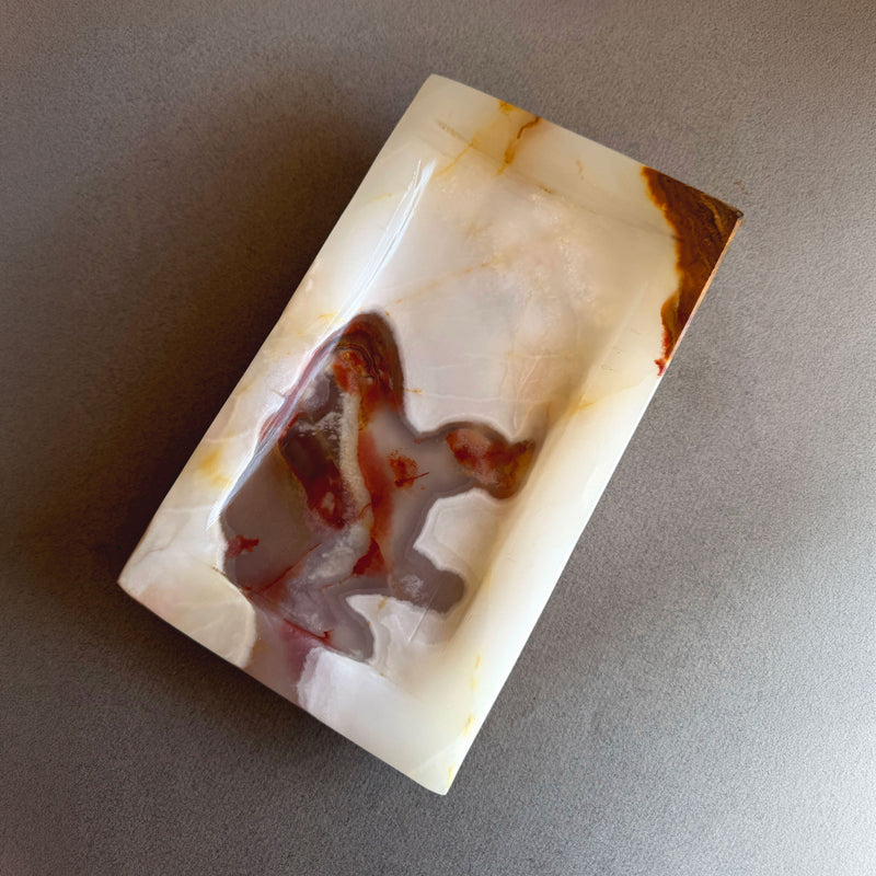 Rectangular stone onyx catchall tray with pink ivory marbled pattern on a gray surface