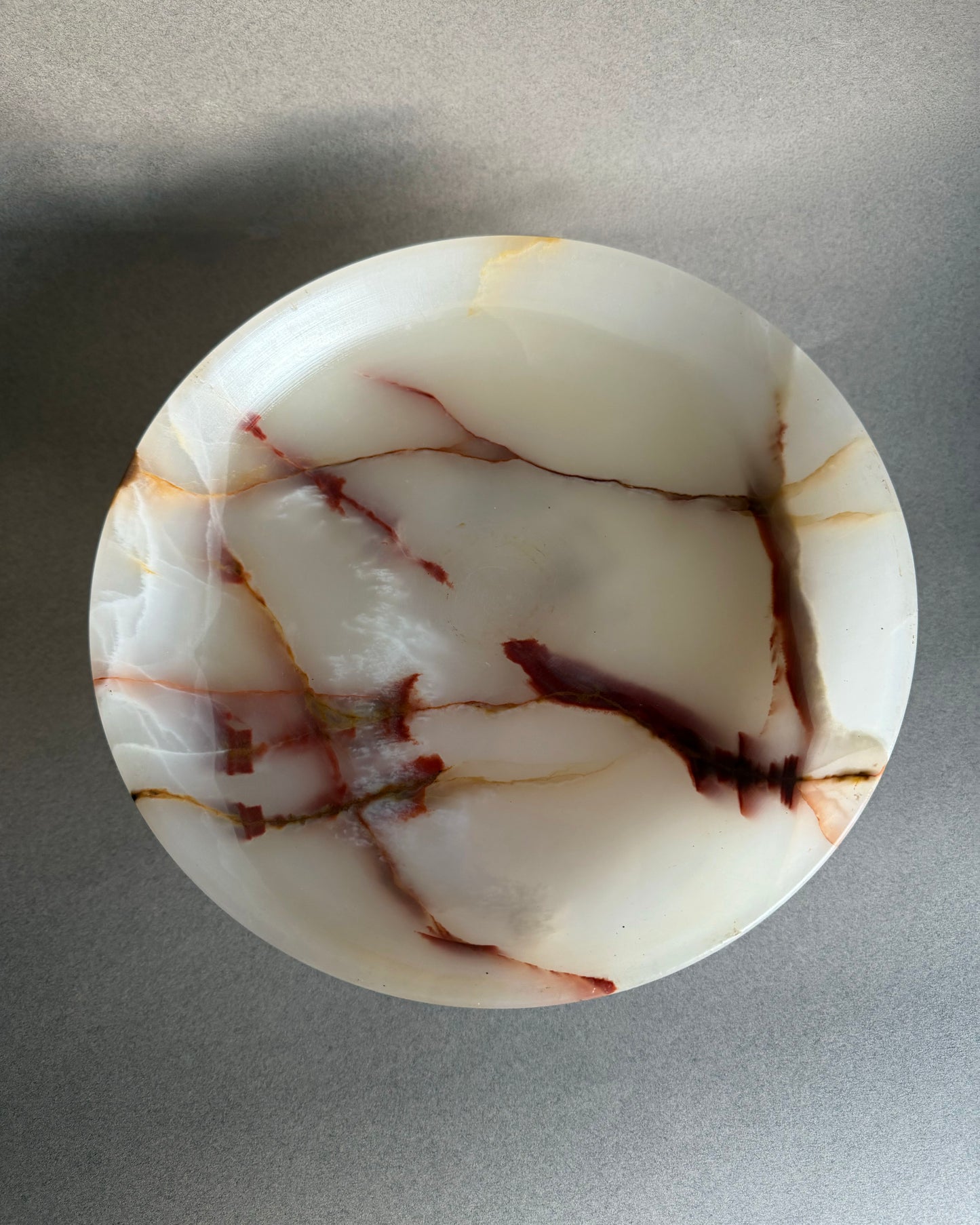 Marble-patterned pink onyx stone bowl on a gray background