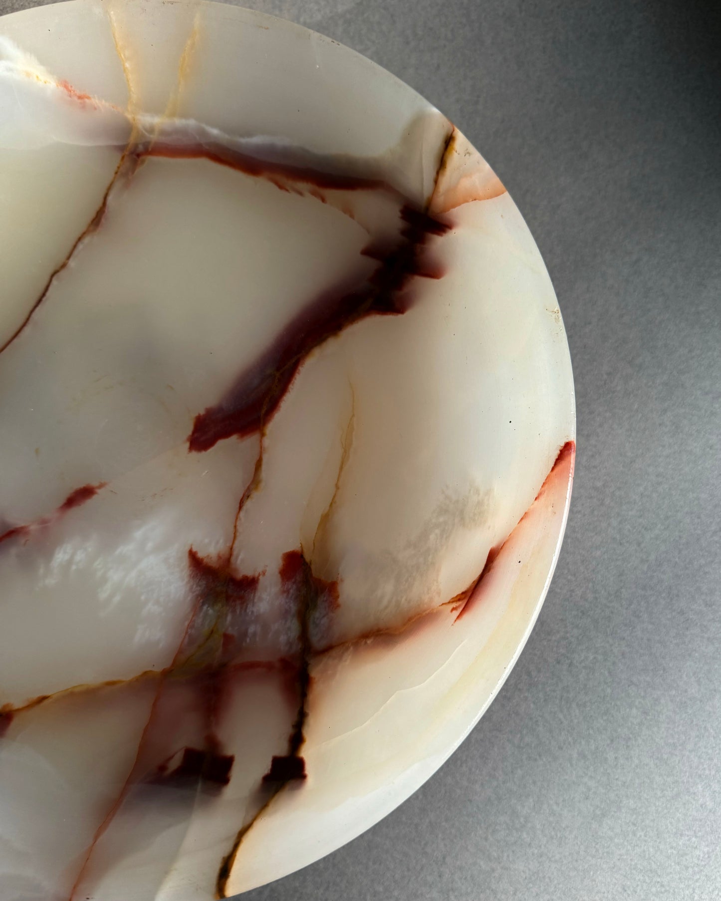 Close-up of a marbled pink stone with brown and beige patterns on a gray background