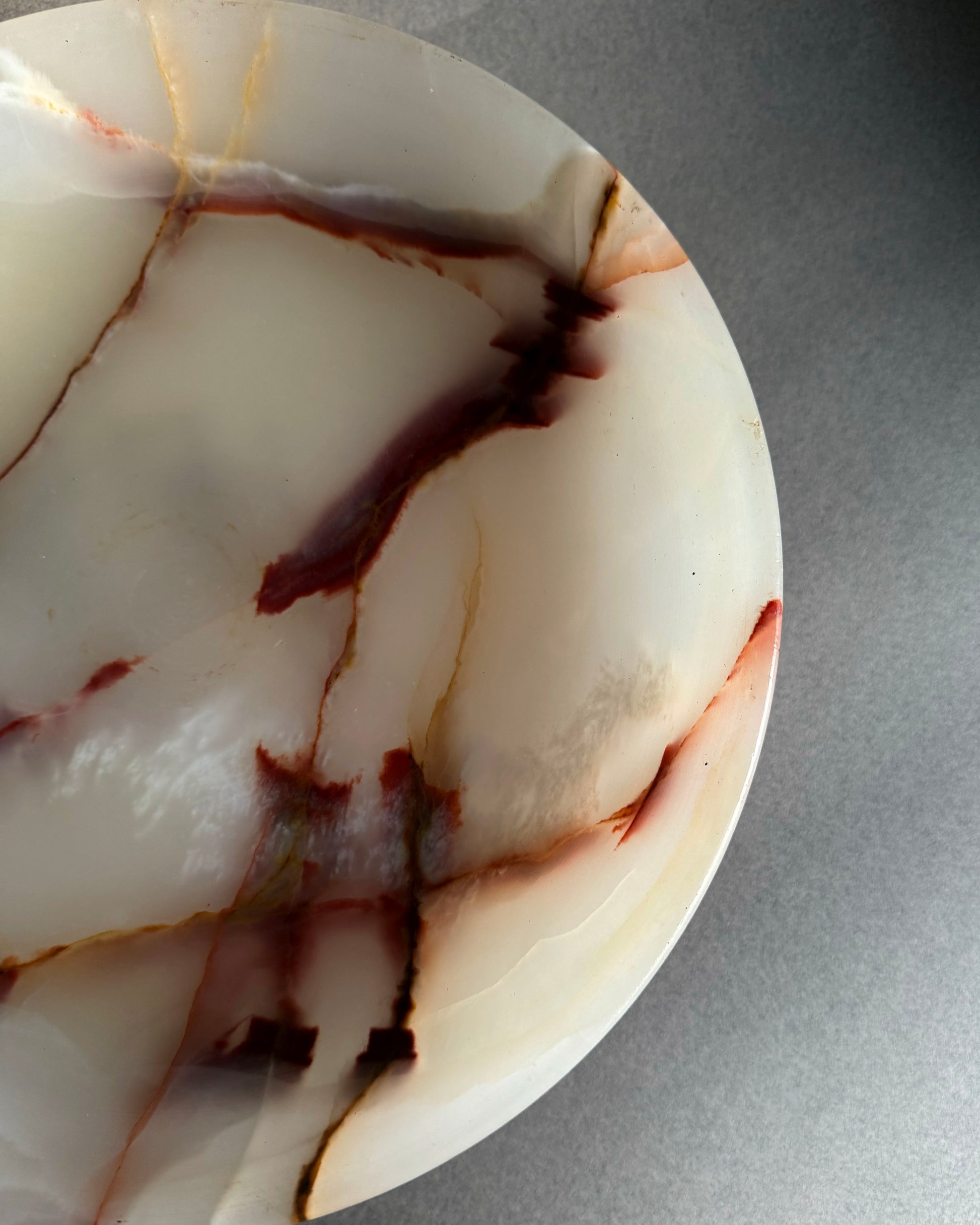 Close-up of a marbled pink stone with brown and beige patterns on a gray background