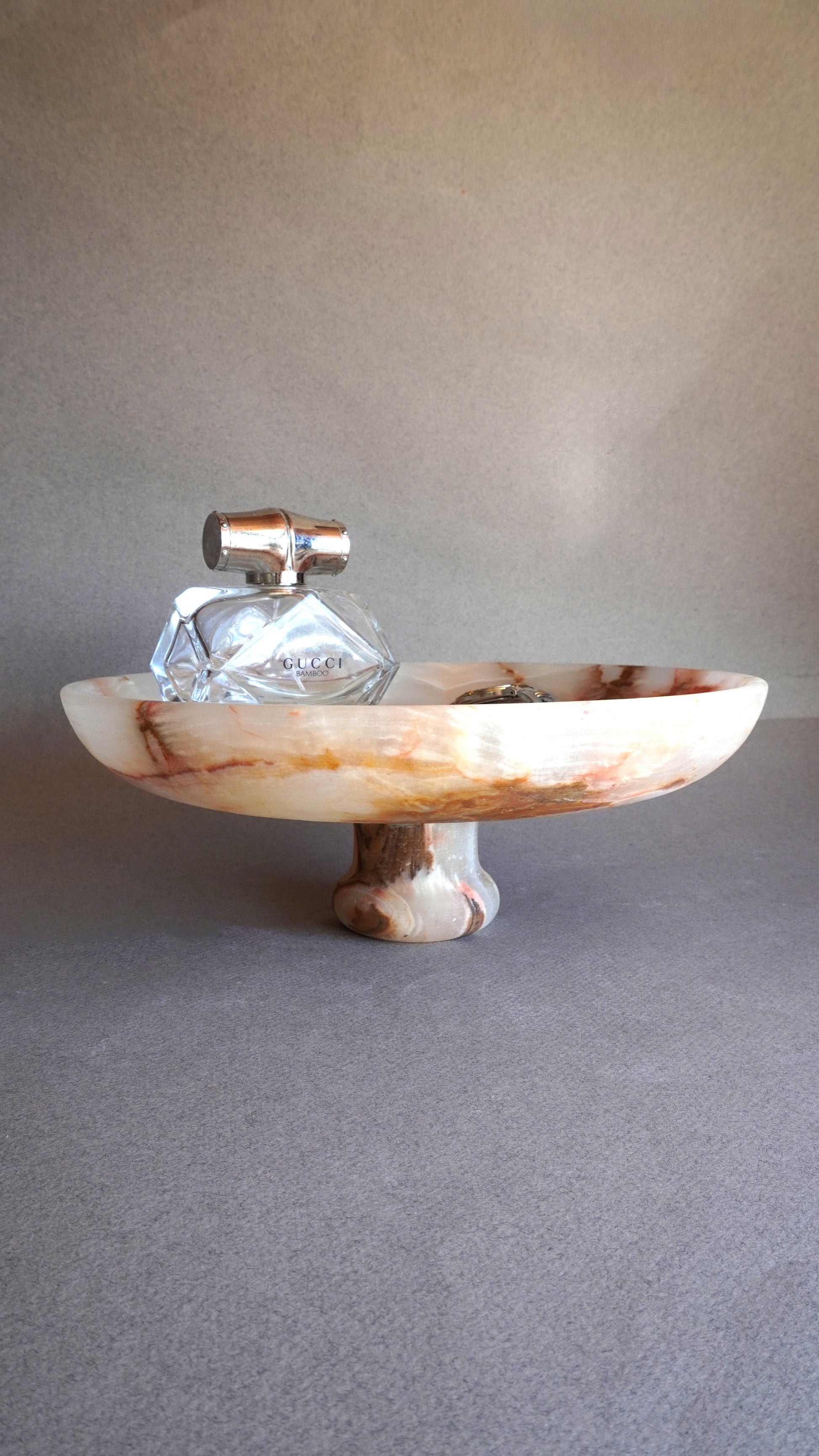 pink onyx Decorative bowl with a glass item on a gray surface