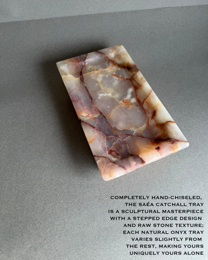 Marble-patterned catchall tray on a gray surface with descriptive text. Close up of blush and ivory onyx stone with natural translucency
