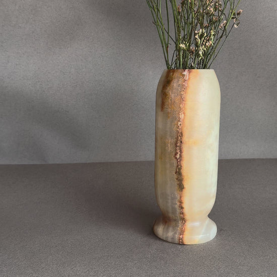Hand-carved peach and amber onyx pedestal vase with ivory stone and natural brown veining, styled with dried florals
