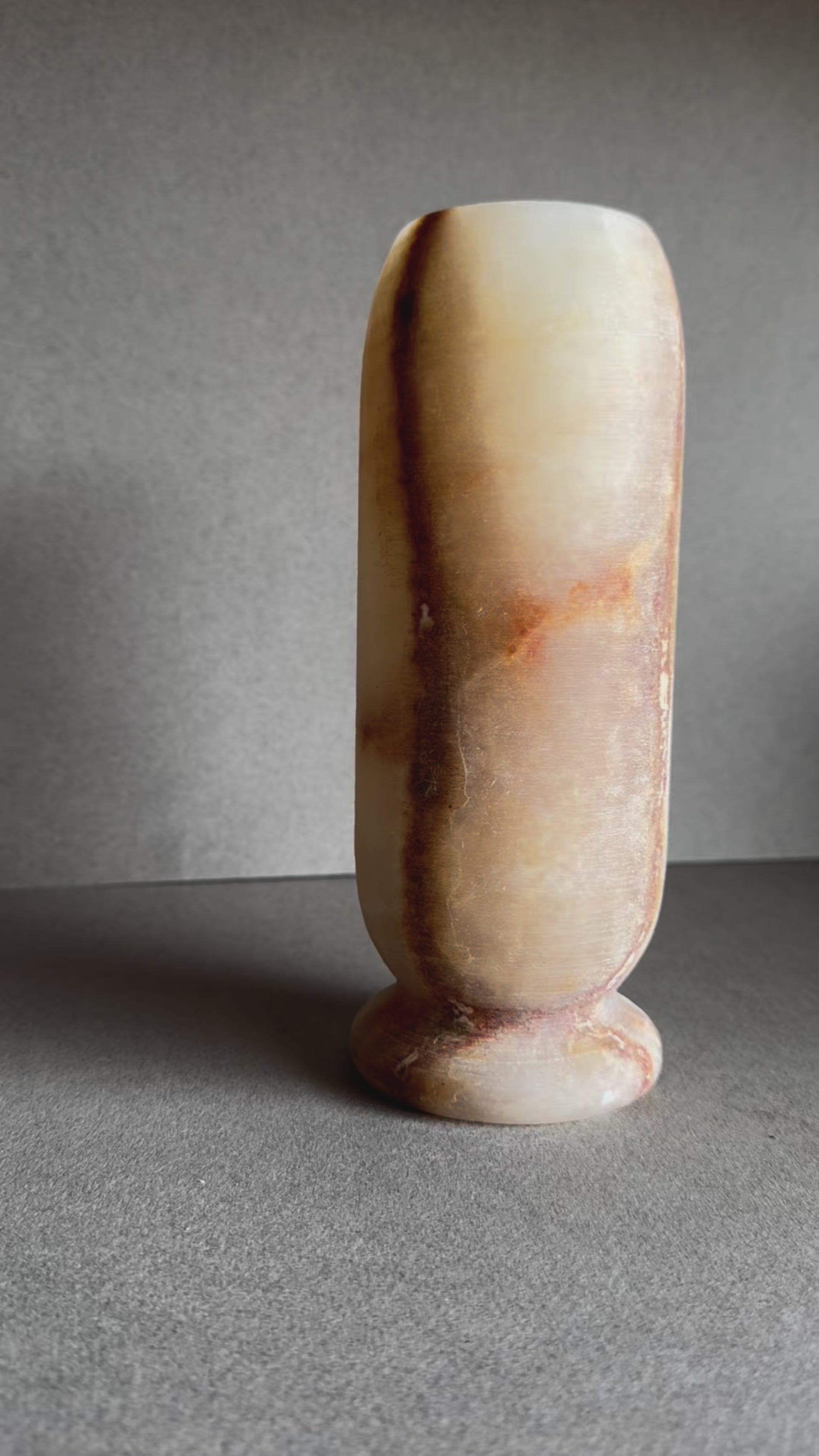 Onyx vase in soft honey and peach tones with marbled amber mineral bloom on front.

