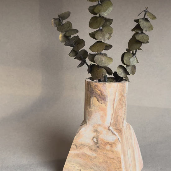Hand-carved dune onyx vase with sculptural square base and cylindrical top, styled with eucalyptus stems.