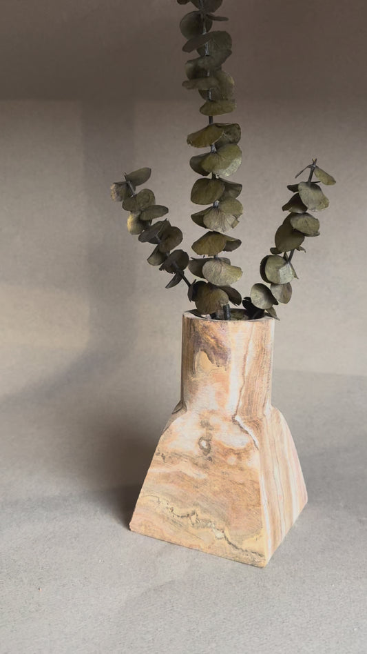 Hand-carved dune onyx vase with sculptural square base and cylindrical top, styled with eucalyptus stems.