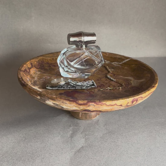Footed onyx pedestal bowl showing earthy brown and amber veining, artisan stone centerpiece for rustic or modern decor.