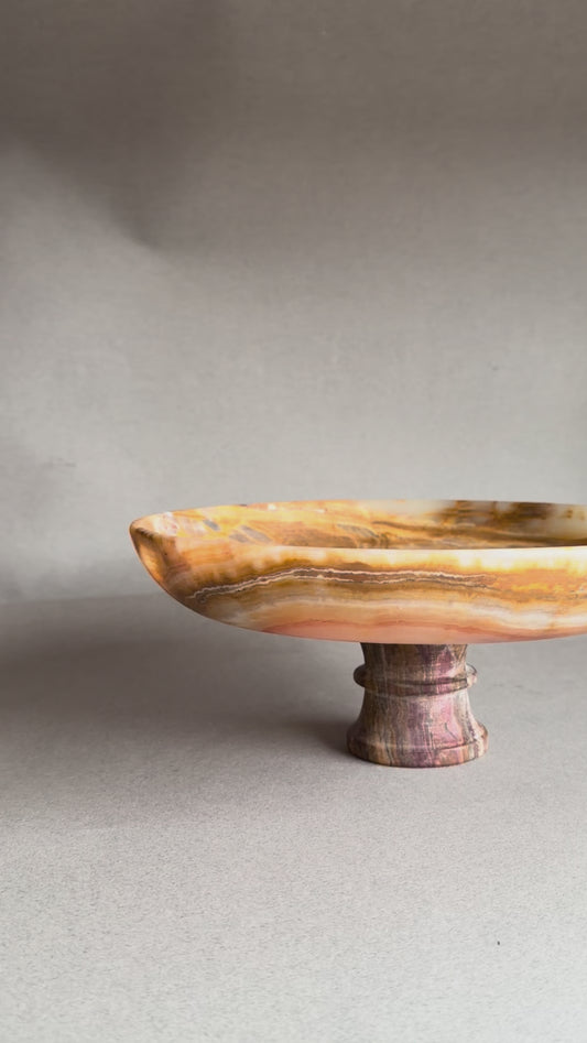 Top view of natural onyx pedestal bowl showing swirling amber and cream stone patterns
