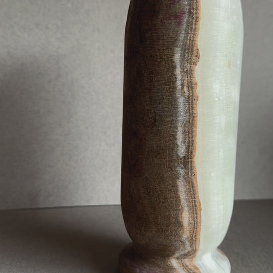 Hand-carved onyx vase with walnut, blush, and ivory veining in a tall cylindrical form.

