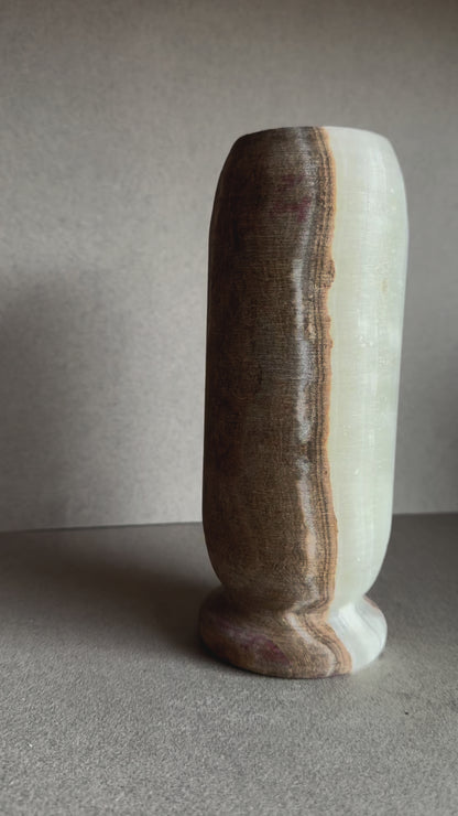 Hand-carved onyx vase with walnut, blush, and ivory veining in a tall cylindrical form.

