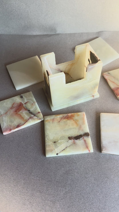 Onyx coaster set with six square stone coasters and a matching holder, ivory and amber colors with natural veining.