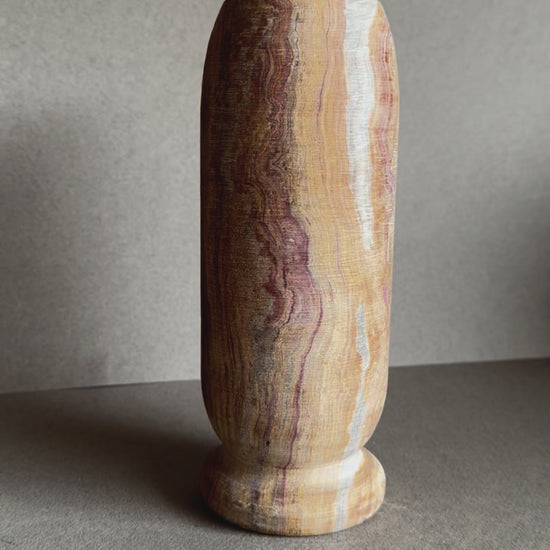 Onyx vase in layered sandstone and rose tones with smooth matte finish and cylindrical shape.

