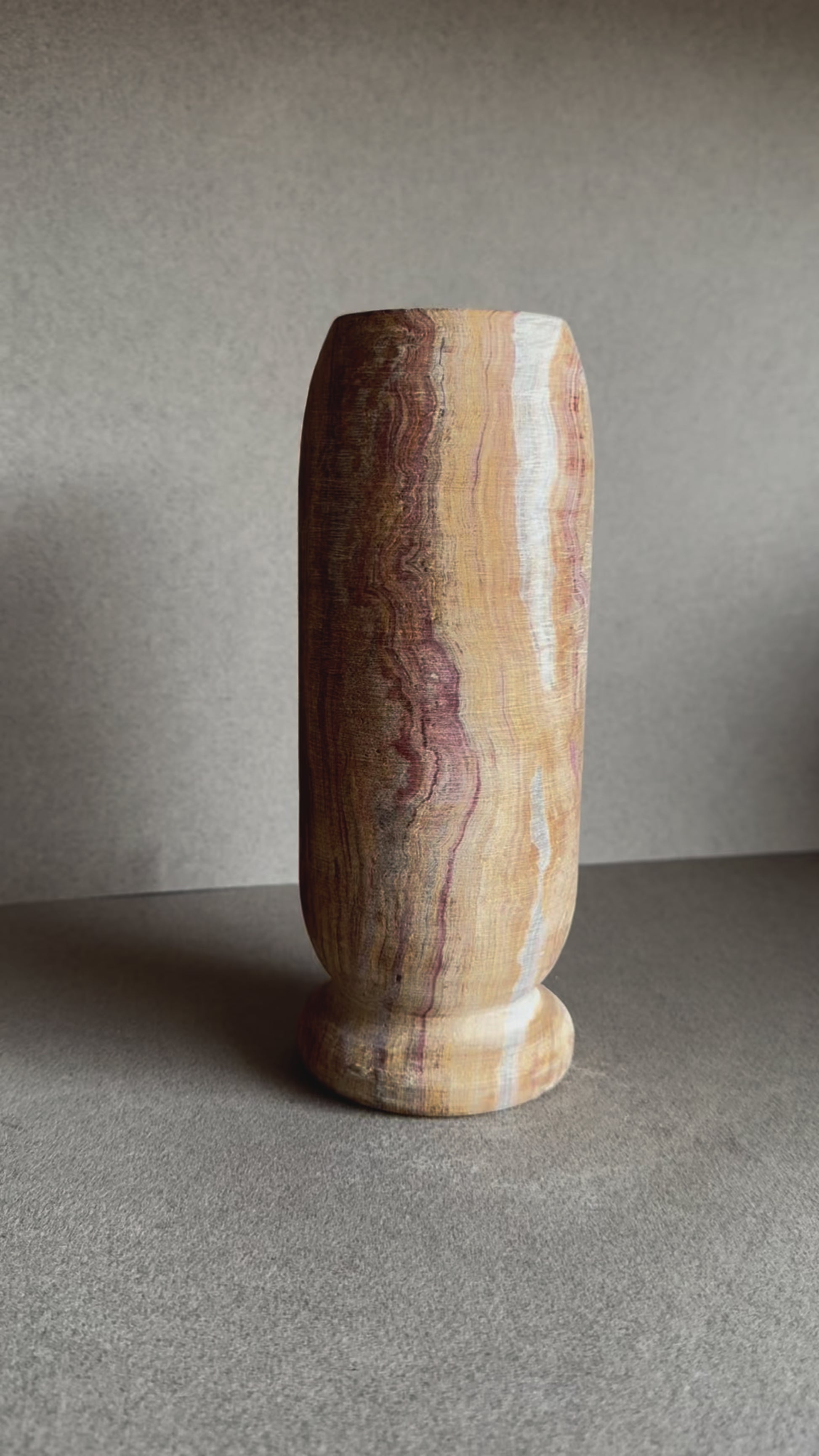 Onyx vase in layered sandstone and rose tones with smooth matte finish and cylindrical shape.

