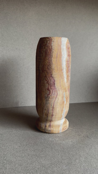 Onyx vase in layered sandstone and rose tones with smooth matte finish and cylindrical shape.

