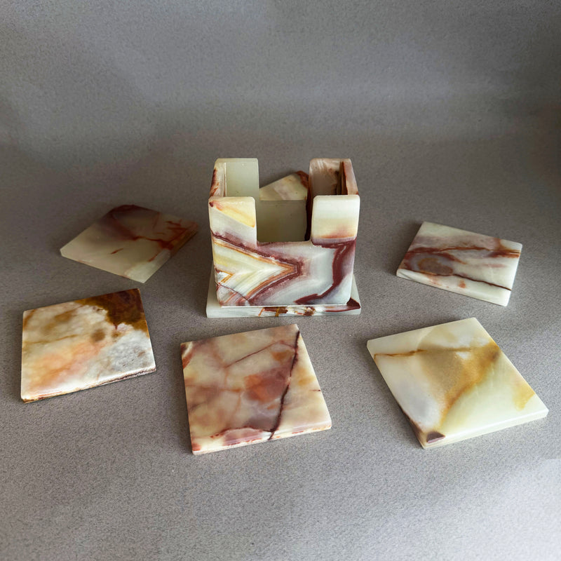 Natural onyx coaster with linear honey and blush veining showcasing raw unpolished stone texture

