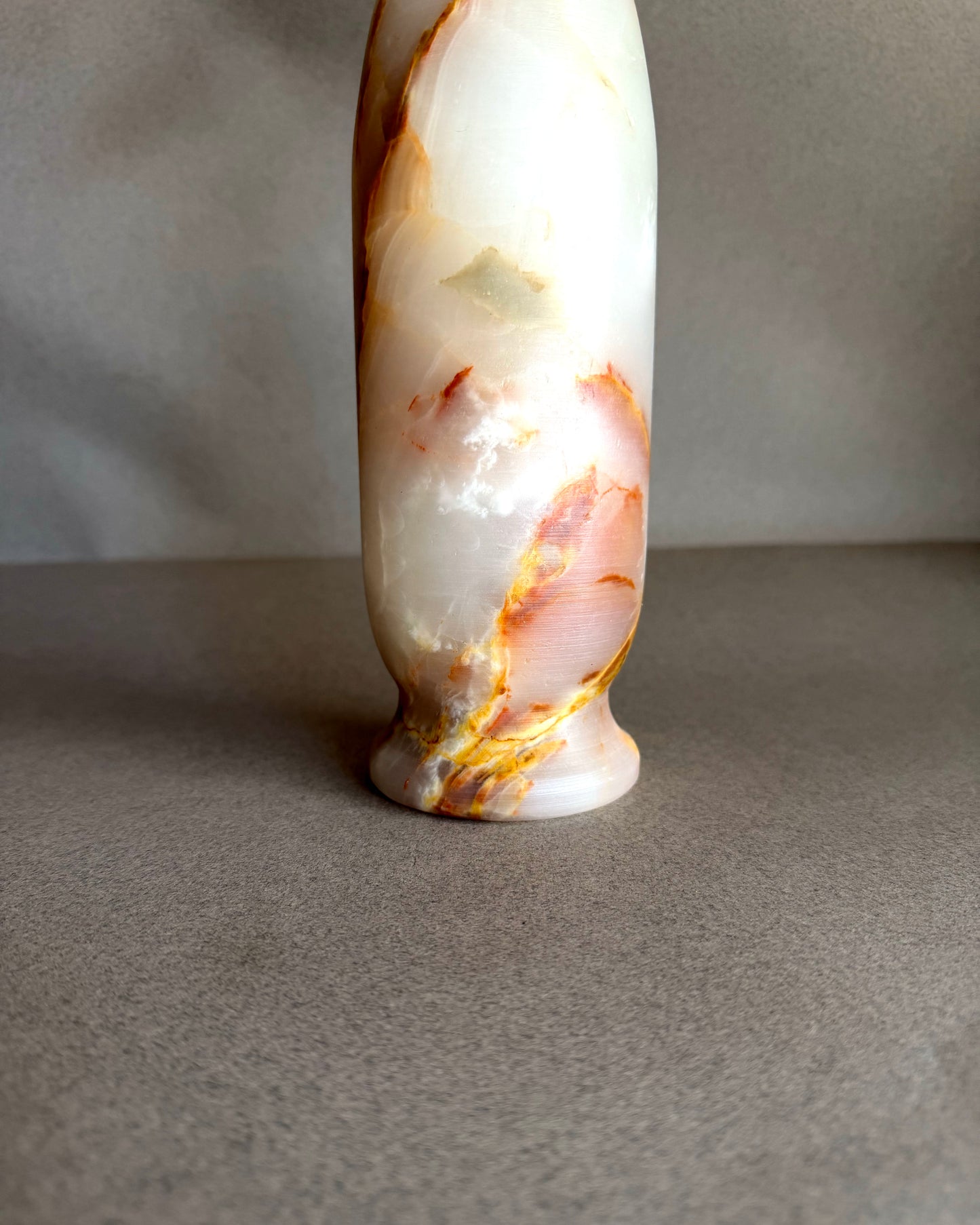 Tall cylindrical onyx vase in cream, blush pink, and warm honey tones with natural stone veining and rounded pedestal base
