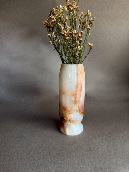 Decorative vase with a natural stone pattern containing dried flowers on a gray background