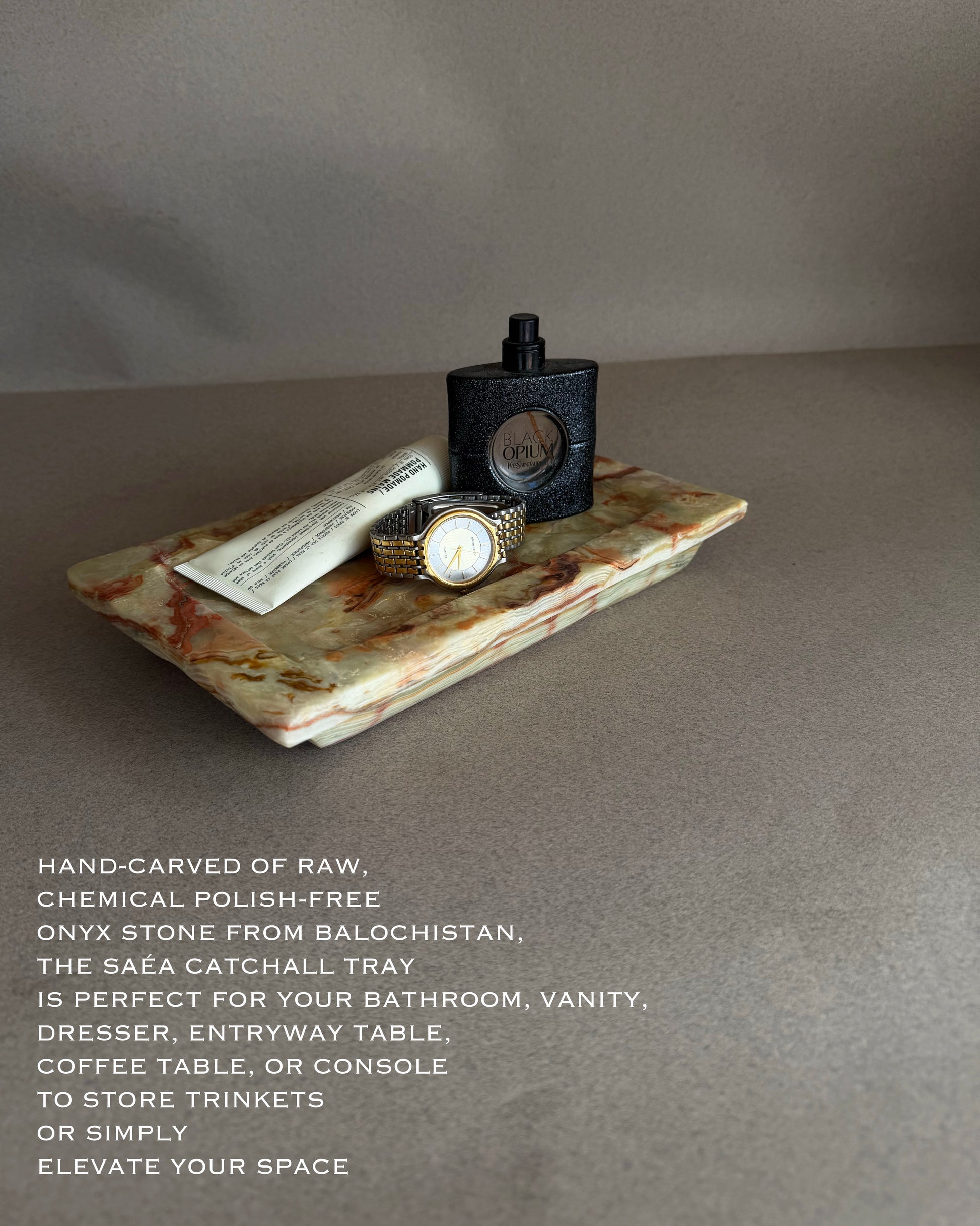 Decorative stone tray with a watch and perfume bottle on a gray background