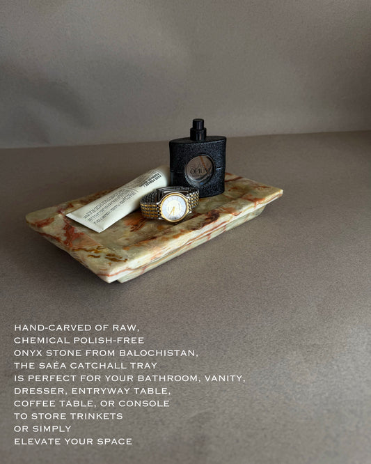 Decorative stone tray with a watch and perfume bottle on a gray background