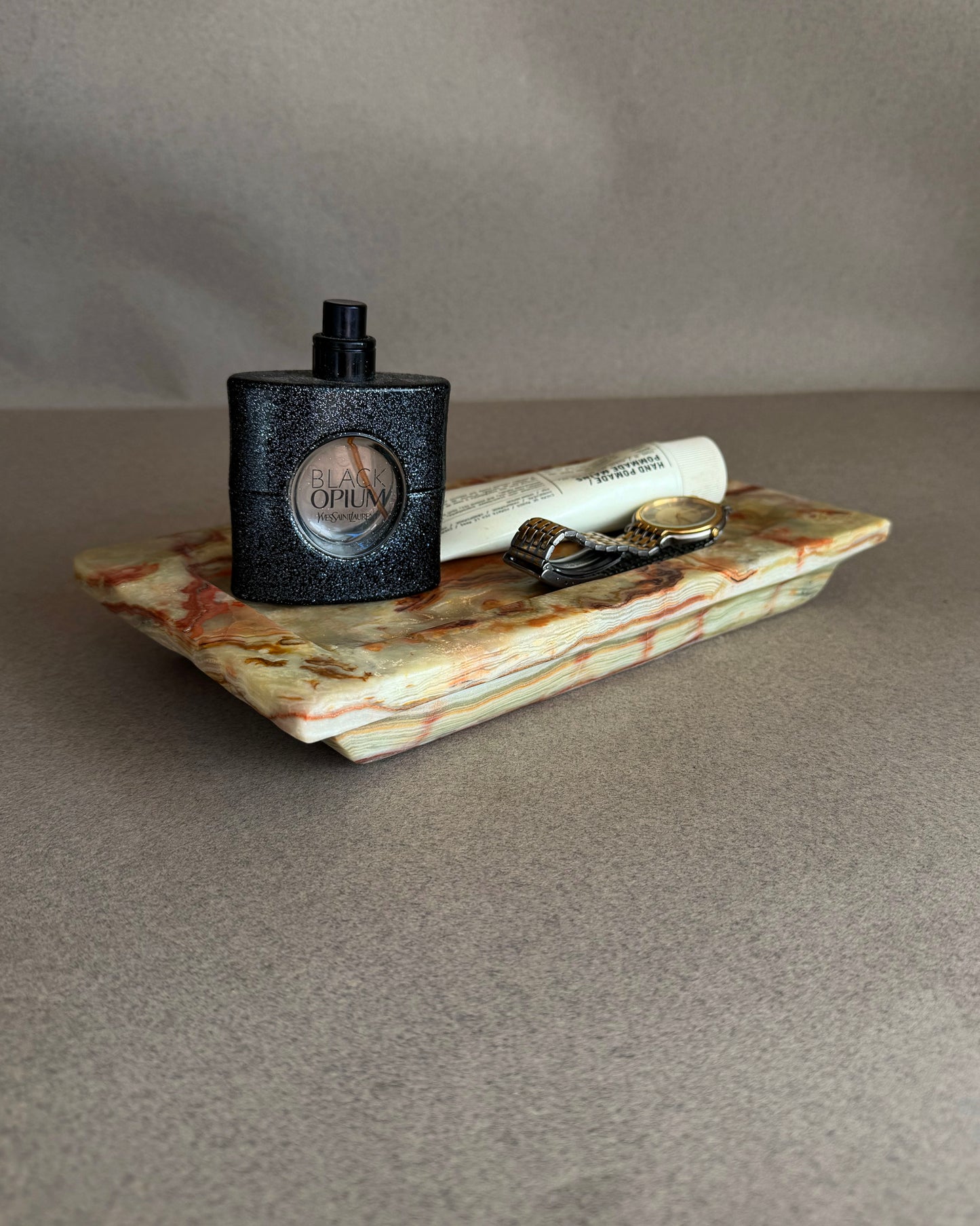 Perfume bottle on a decorative stone tray with a gray background