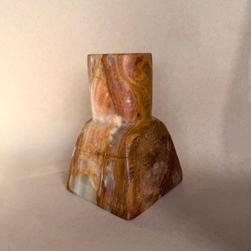 Decorative red brown green onyx vase with dried flowers on a neutral background