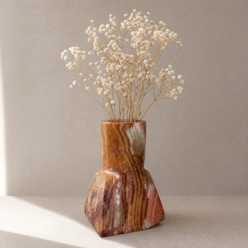 Decorative red brown onyx vase with dried flowers on a neutral background
