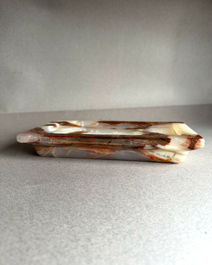 Decorative stone tray with brown and white marbled pattern on a gray background