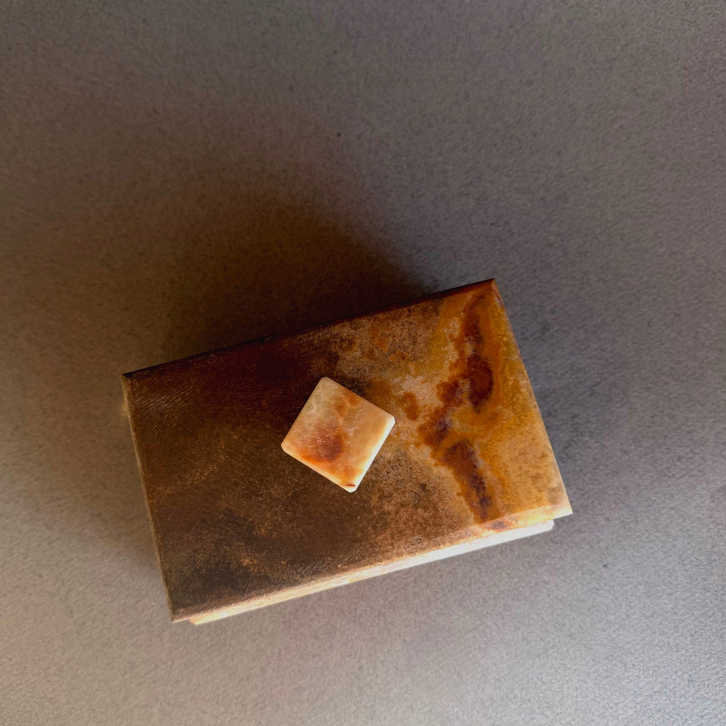 Rust-colored rectangular object with a square piece on a gray background