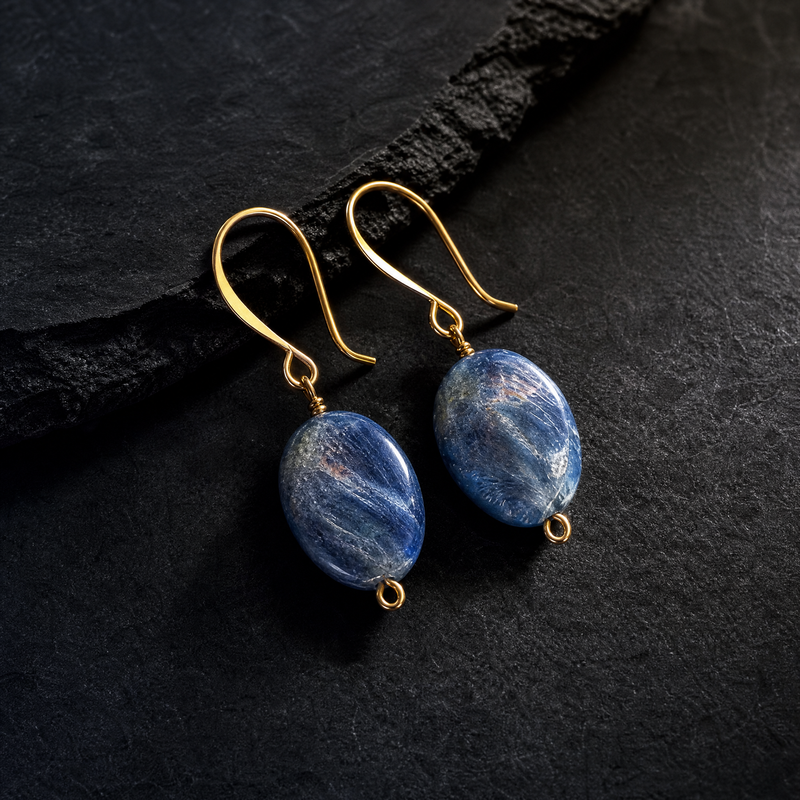 Pair of blue kyanite stone earrings with gold hooks on a dark surface