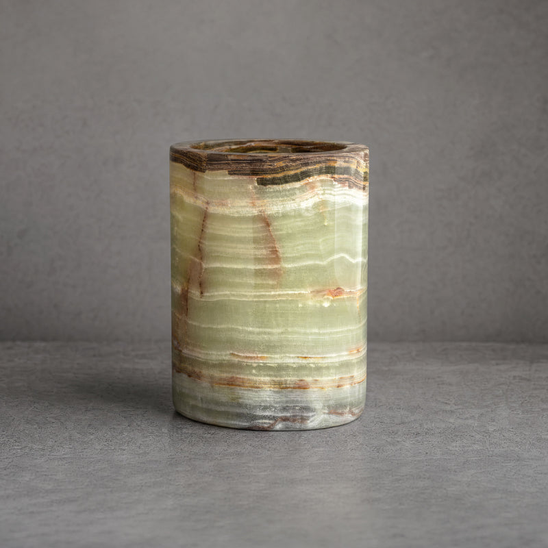 Hand-carved green onyx vessel in sage, jade, and ivory with rust veining and a deep brown banded rim on a neutral gray background
