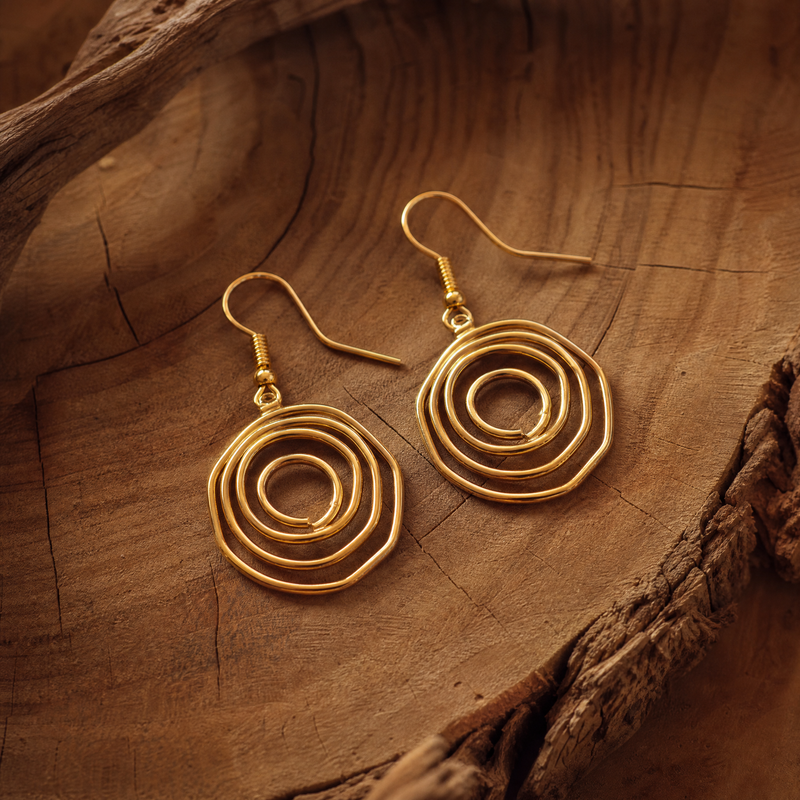 SAÉA Gold spiral earrings on a wooden surface