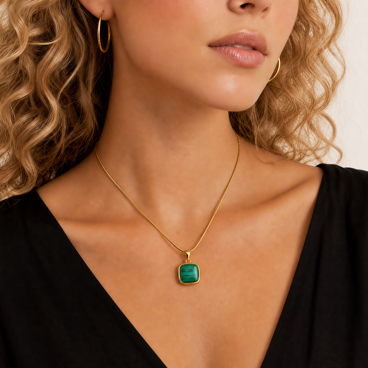 Woman wearing a gold snake chain necklace with a green malachite pendant