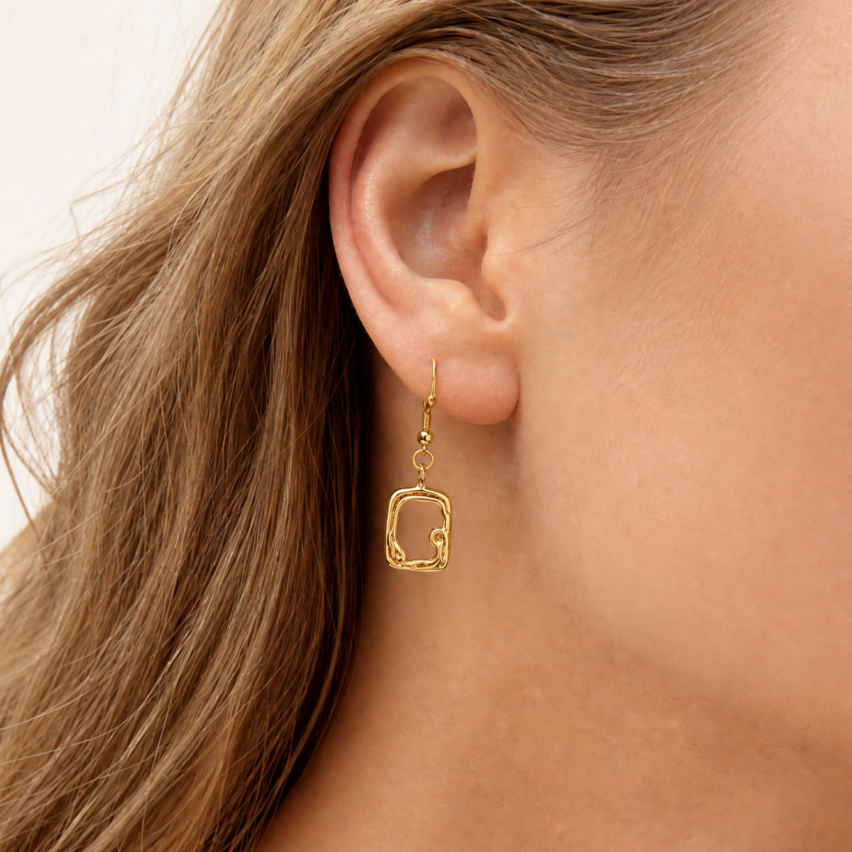 molten Gold sculptural earring worn by a person with light brown hair on a neutral background