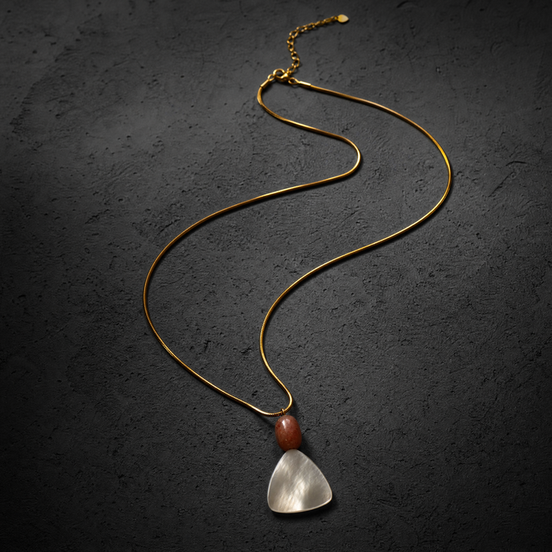 Necklace with a  MOTHER OF PEARL sunstone orange white pendant on a dark textured background