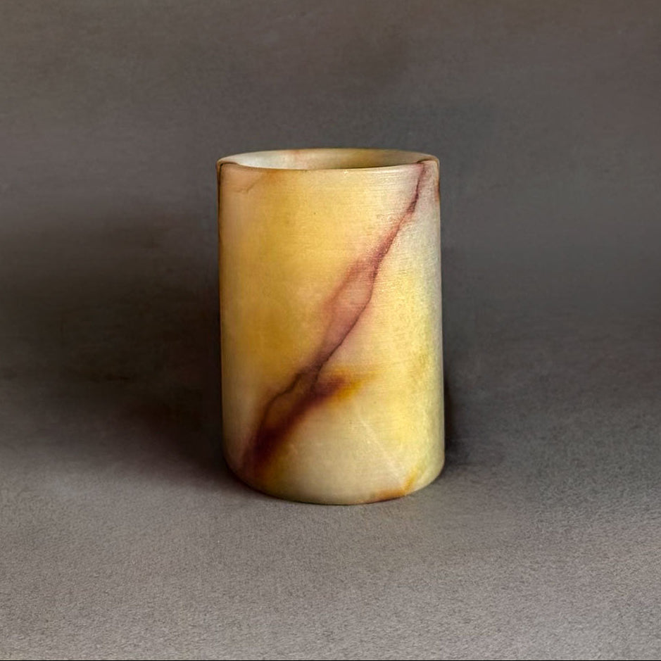Cylindrical onyx rainbow multicolored yellow red jar with marbled design on a gray background