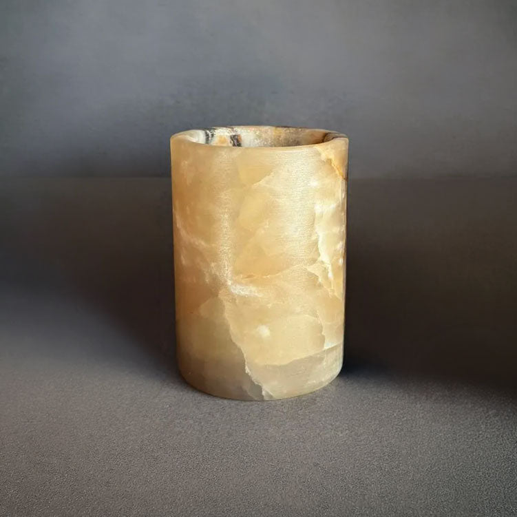 Cylindrical honey onyx yellow stone jar on a gray background